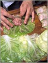 Положить порцию фарша на внутреннюю сторону в основание капустного листа.