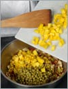Добавить зеленый горошек, кукурузу и манго в кастрюлю, жарить 2 мин. 