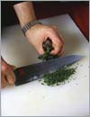 Взять вторую разделочную доску и на ней очень мелко нашинковать свежую зелень петрушки с помощью хорошо наточенного ножа для овощей.