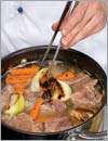Лук и морковь очистить, крупно нарезать, вместе с корнем петрушки слегка припечь на сухой раскаленной сковороде, добавить в кастрюлю с мясом, уменьшить огонь до минимума.