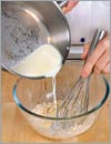 Вымешивая тесто венчиком, добавить теплое молоко и размягченное сливочное масло.
